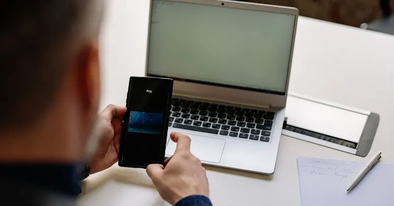 Muž potvrzuje platbu v mobilu u notebooku