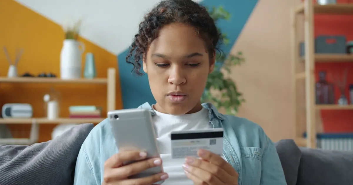 Žena drží telefon a platební kartu