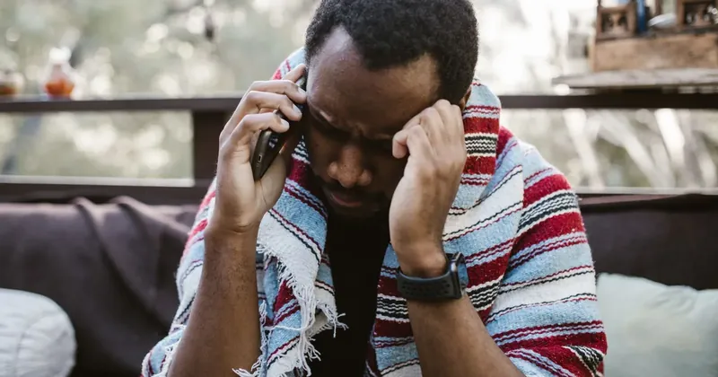 Ustaraný muž telefonuje a drží se za hlavu