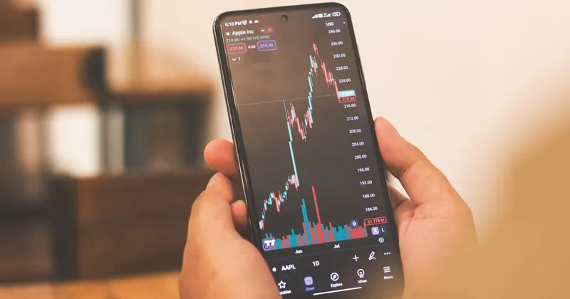 Ruce drží telefon s grafem burzovního kurzu