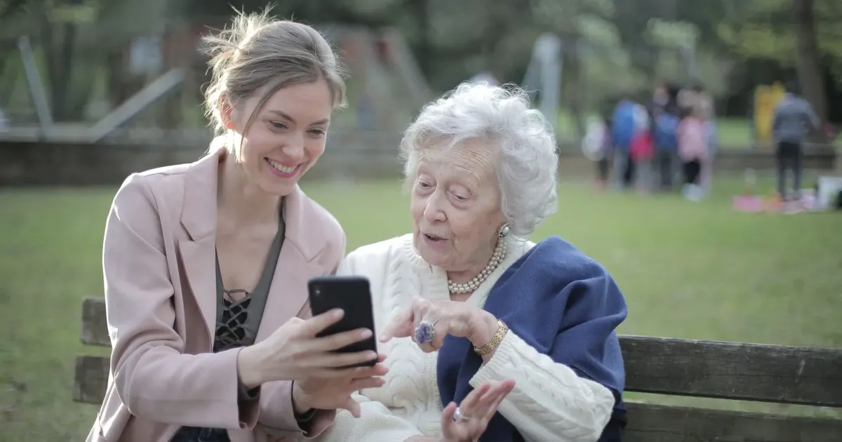 Mladá žena ukazuje starší paní, jak používat telefon