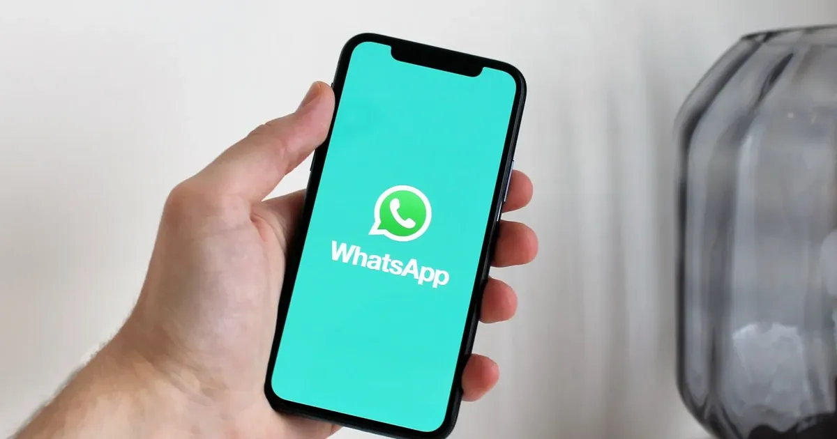 Ruka drží telefon s logem WhatsAppu