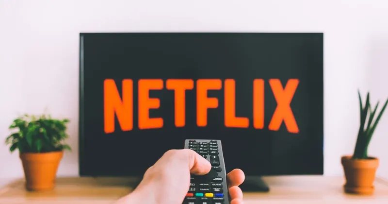Televize s logem Netflixu a ruka s ovladačem