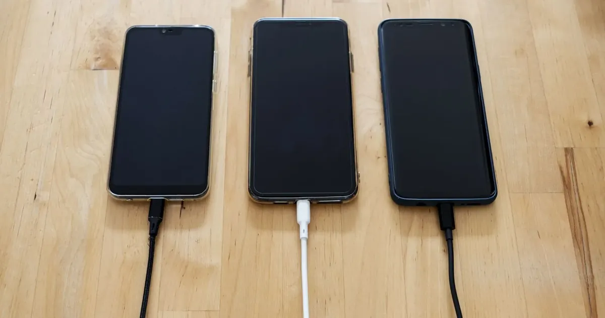 Tři telefony připojené k nabíjecím kabelům