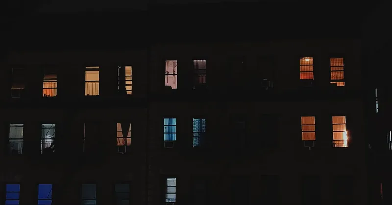 Rozsvícená okna panelového domu v noci
