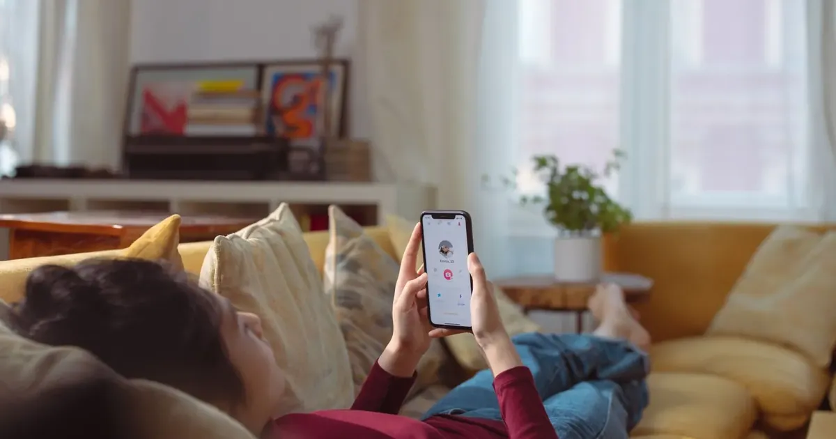 Žena leží na pohovce a dívá se do telefonu