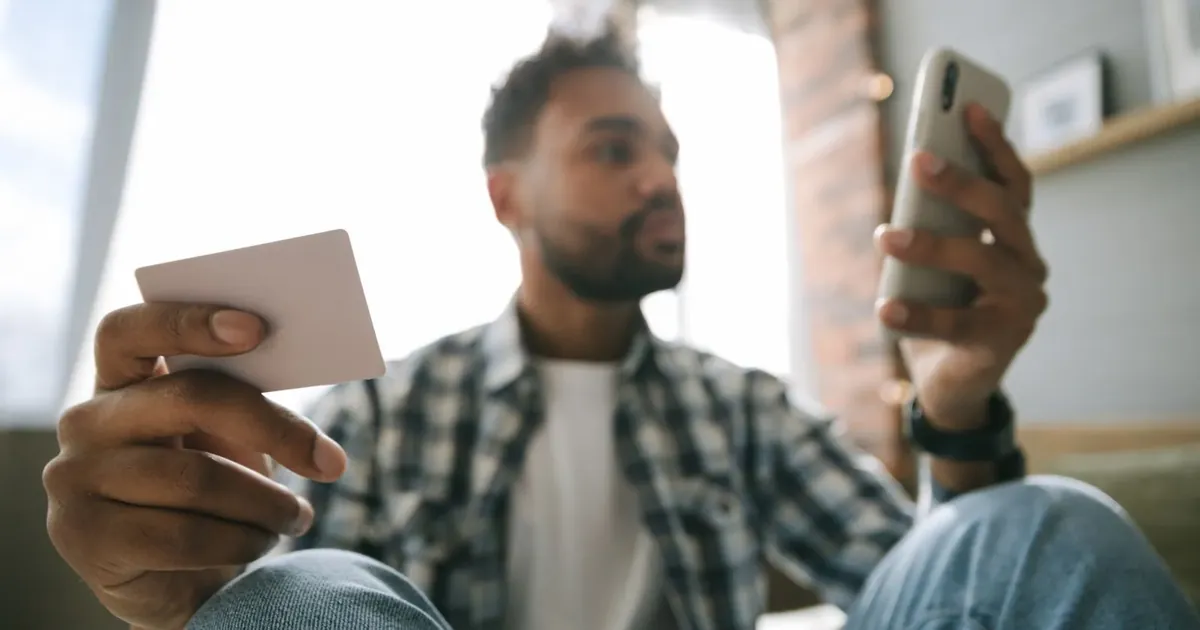 Muž drží platební kartu a telefon