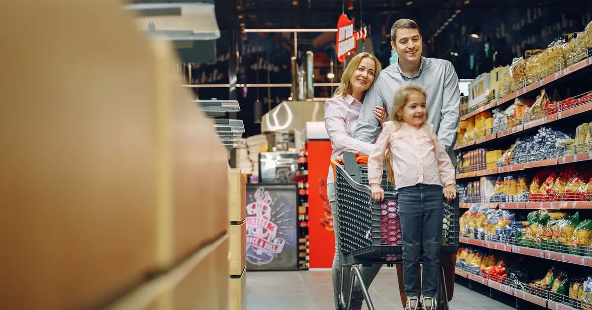 Rodina s nákupním vozíkem v uličce supermarketu