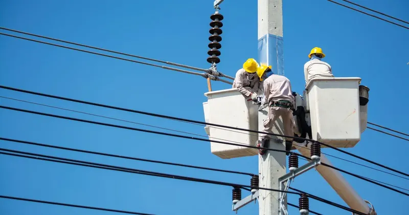 Technici pracují na sloupu elektrického vedení