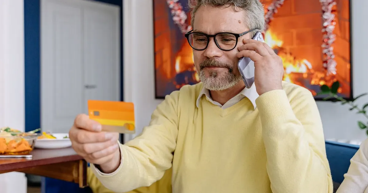 Muž telefonuje a v ruce drží platební kartu