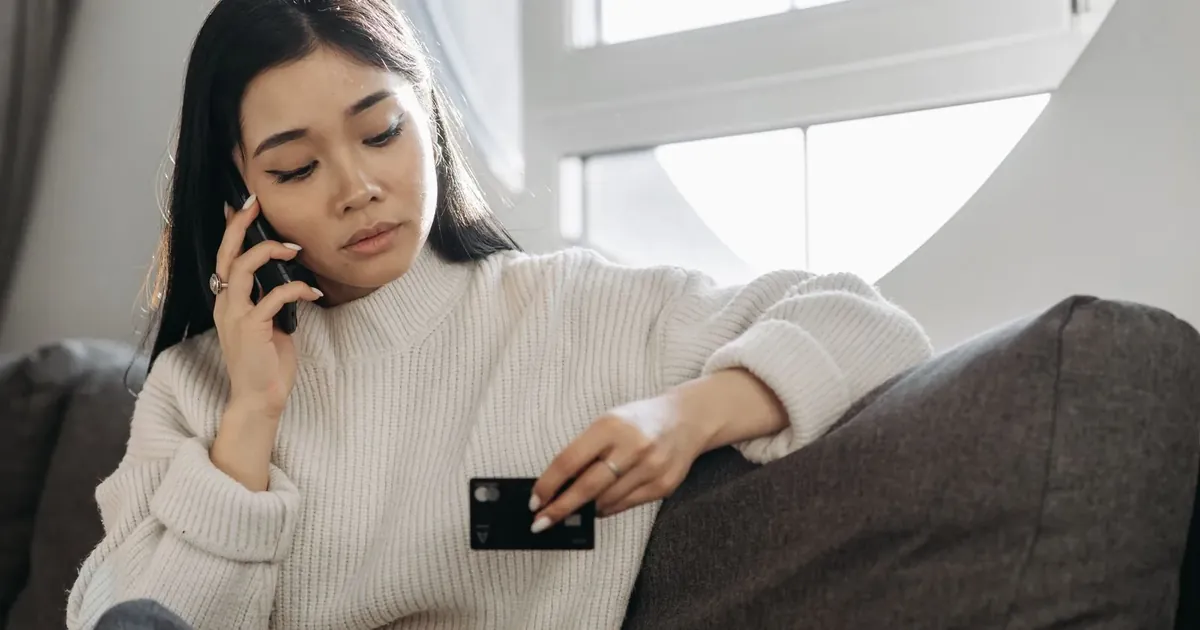Žena telefonuje a drží platební kartu